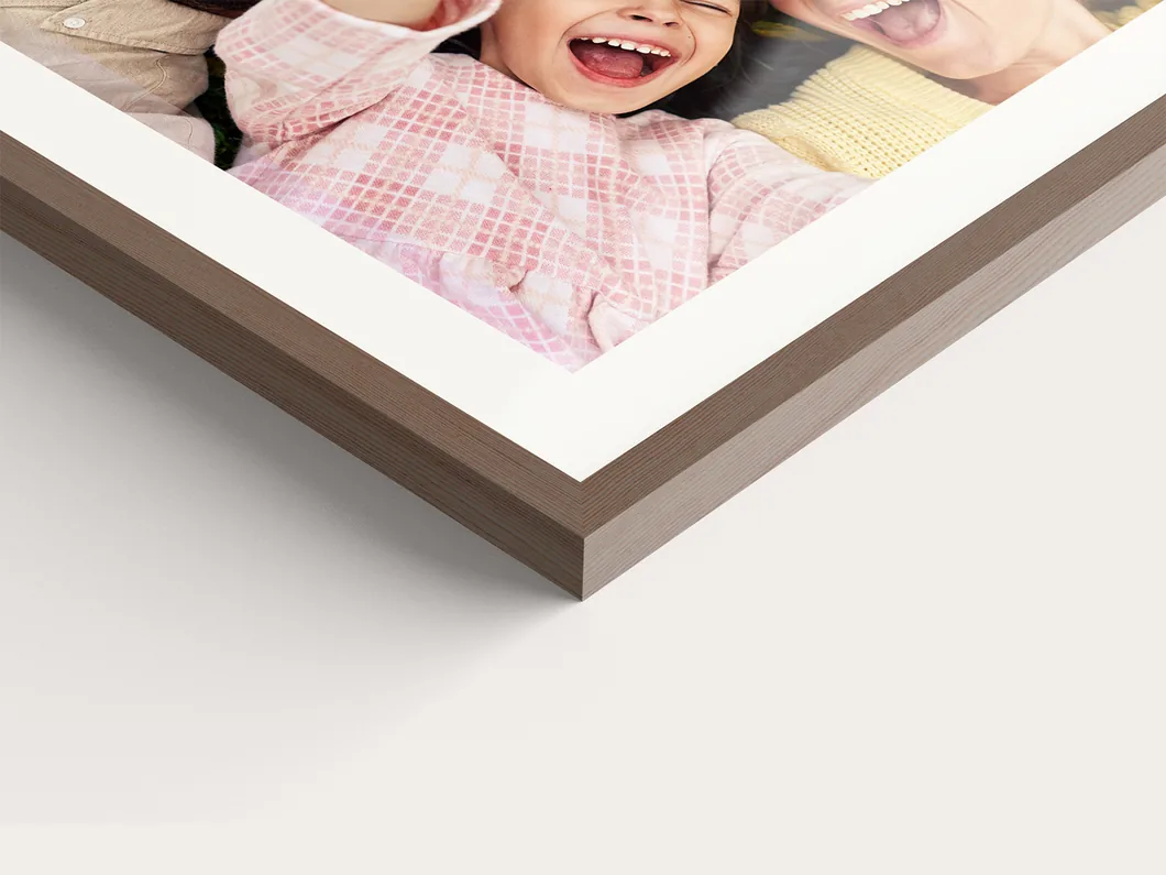 Close view of a framed photo print corner showing the frame profile and the white mat