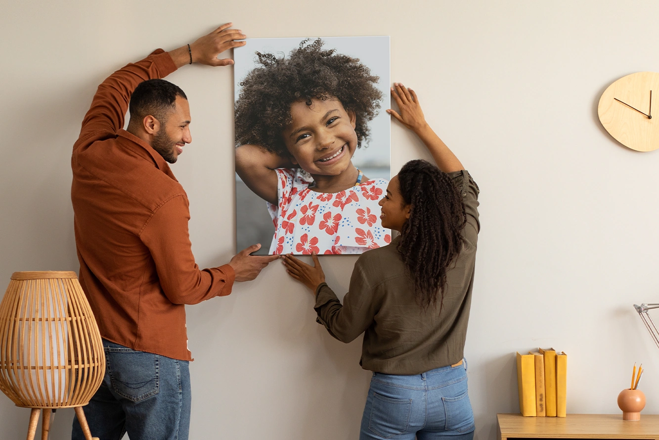 A couple hanging a personalized canvas portrait of their child