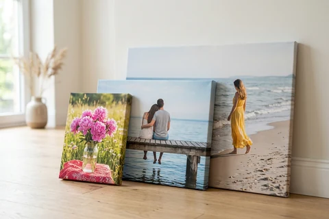 Three photo canvases in different sizes standing side by side against a wall