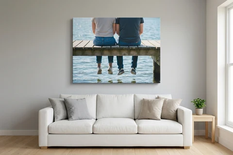 A large landscape photo canvas hung centrally above a sofa, filling about two thirds of the wall behind it