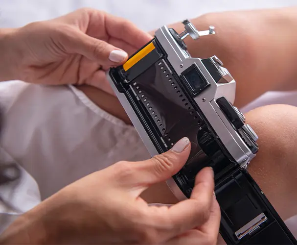 Eine Frau legt gerade einen Kleinbildfilm in ihre analoge Kamera ein