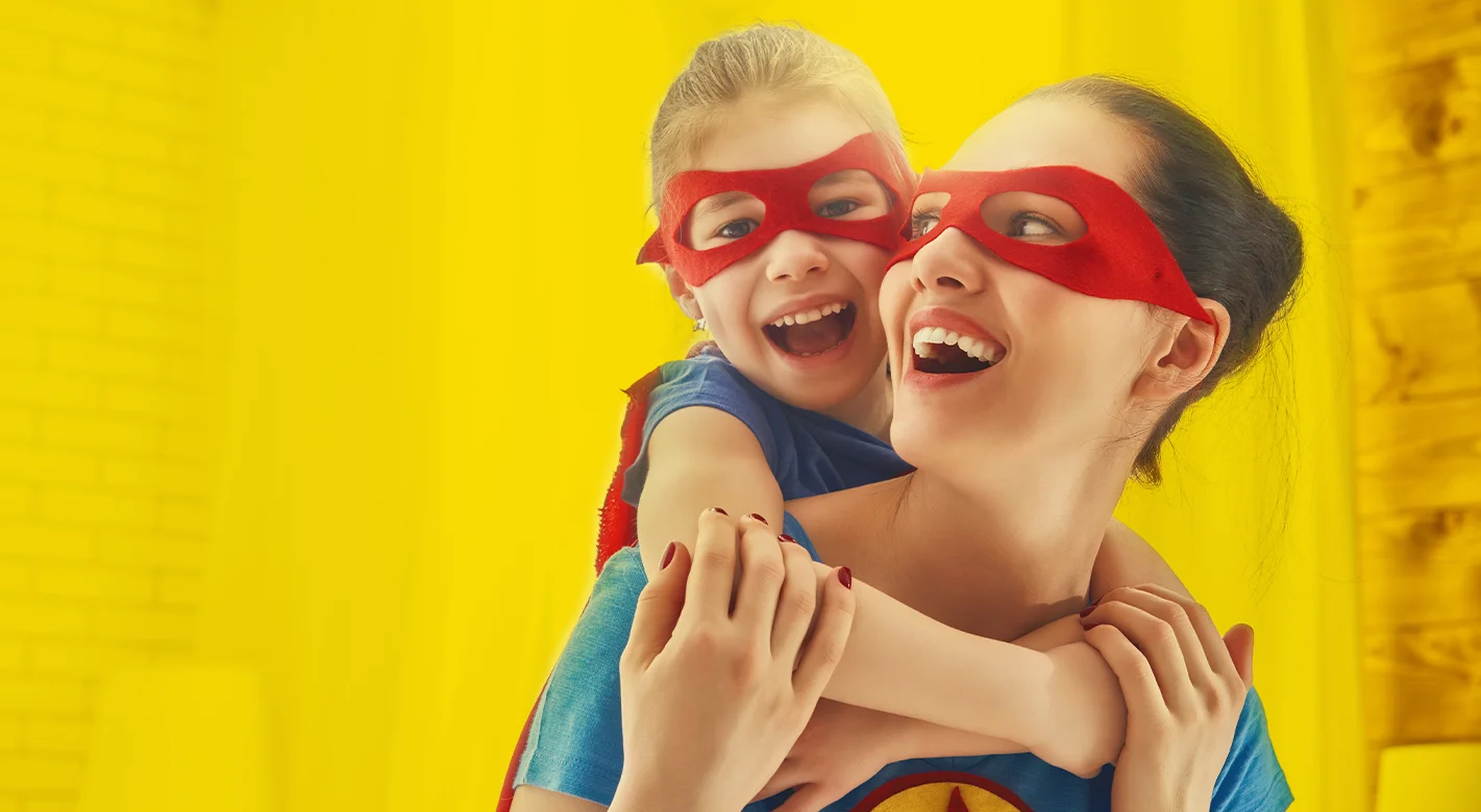 Mutter und Kind mit roten Masken lachen gemeinsam und spielen Superhelden als emotionales Motiv für starke Bindung und kreative Fotogeschenke zum Muttertag