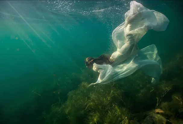 Unterwasseraufnahme einer Frau in weißem Kleid. 10 Tipps für atemberaubende Unterwasserfotos gibt's von ORWO!